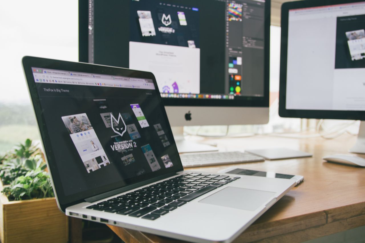 Un espace de travail élégant avec un ordinateur portable et des écrans affichant un logiciel de design.